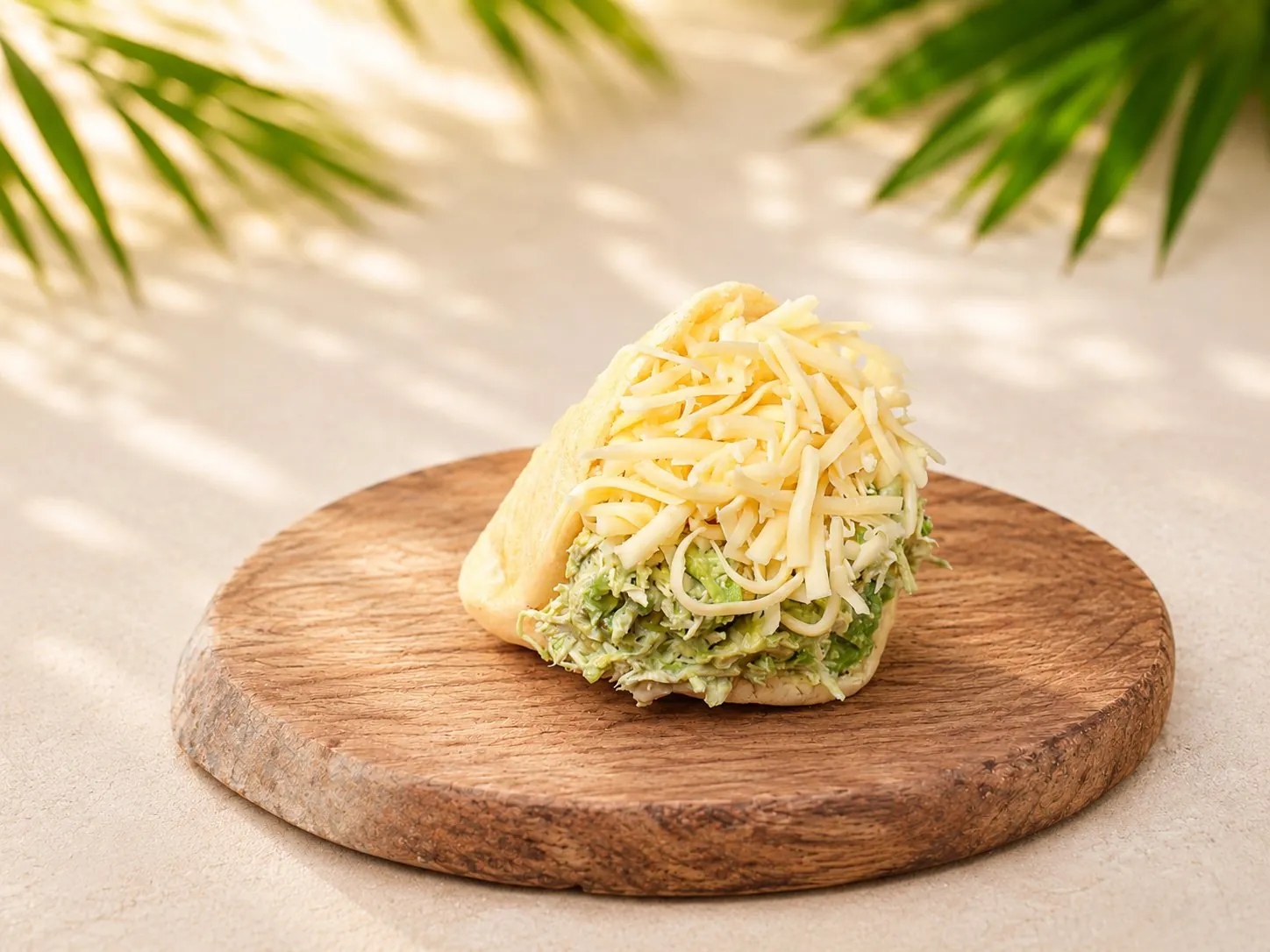 Sifrina Arepa, gefüllt mit Hühnchen und Guacamole, getoppt mit geriebenem Goudakäse, auf einem Holzbrett.