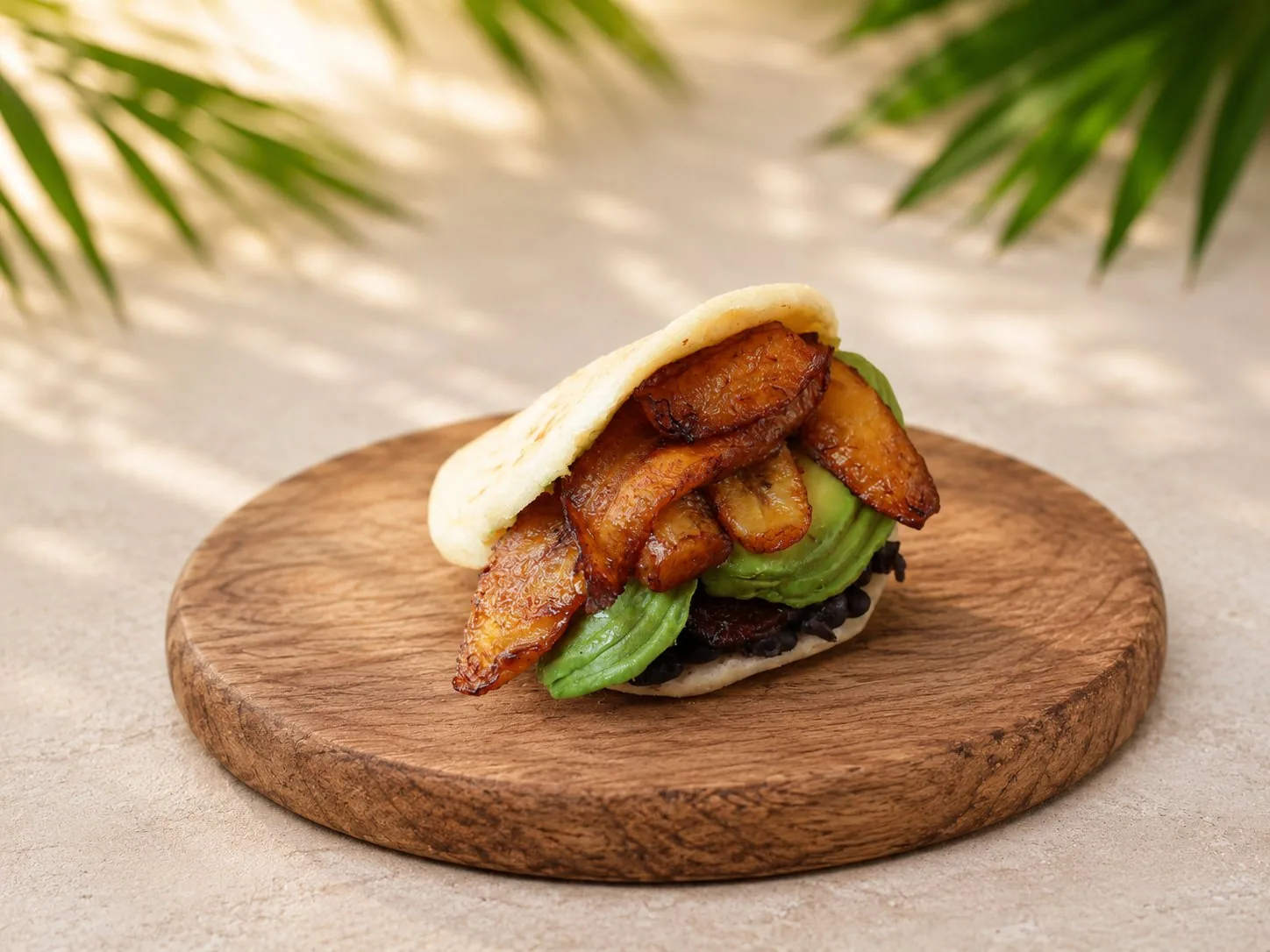 Vegane Arepa mit Avocado, gebratenen Kochbananen und schwarzen Bohnen.