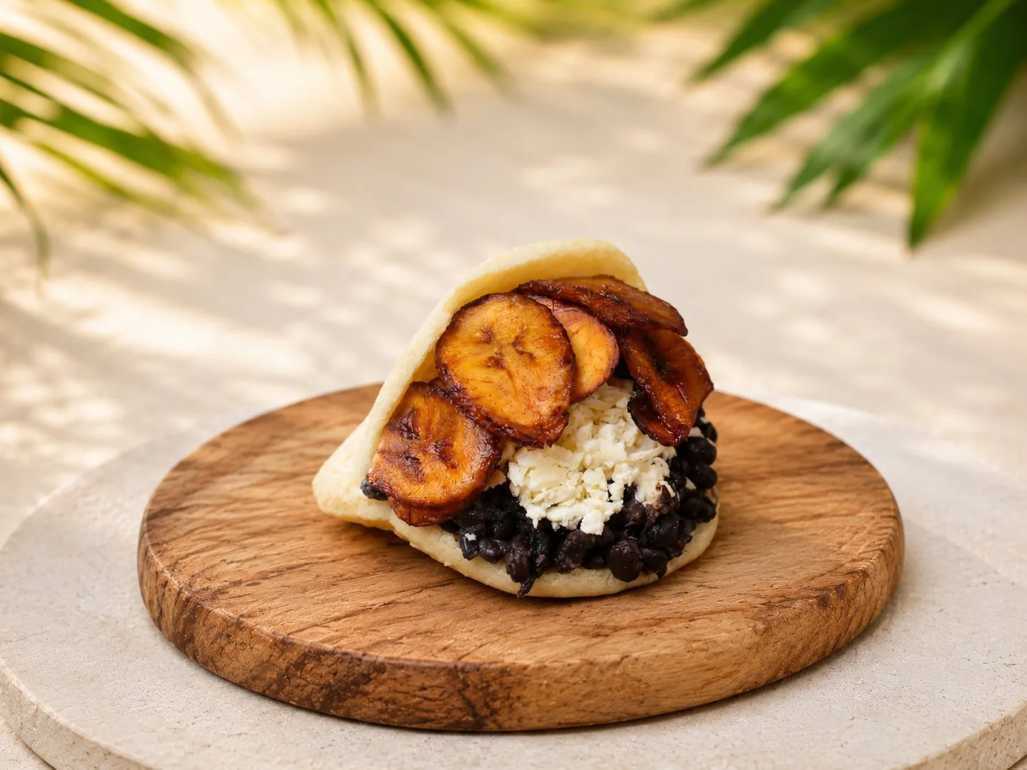 Vegetarische Arepa mit gebratenen Kochbananen, schwarzen Bohnen und Hirtenkäse.