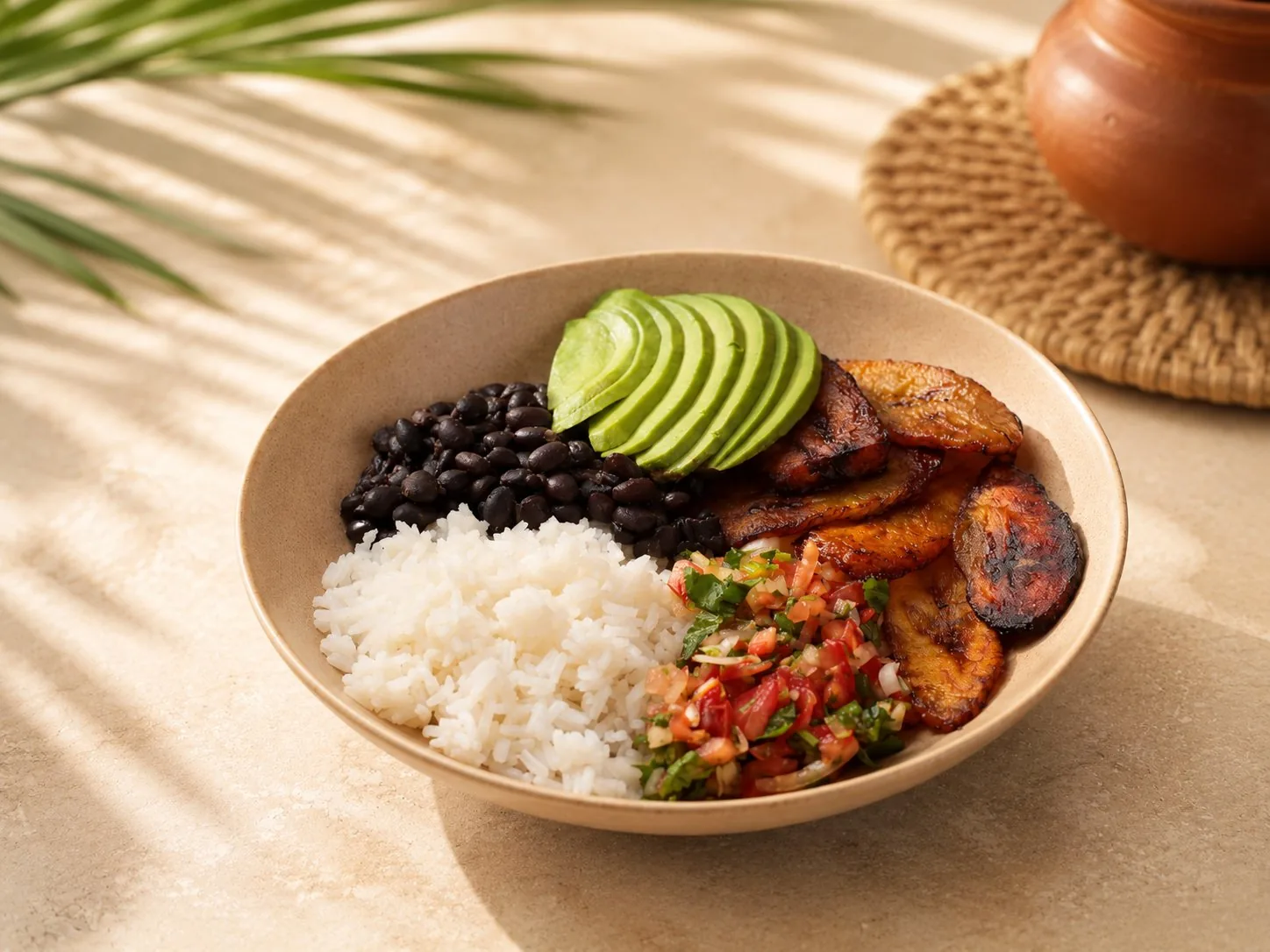 Vegane Bowl mit Reis, schwarzen Bohnen, Avocado, gebratenen Kochbananen und Pico de Gallo.