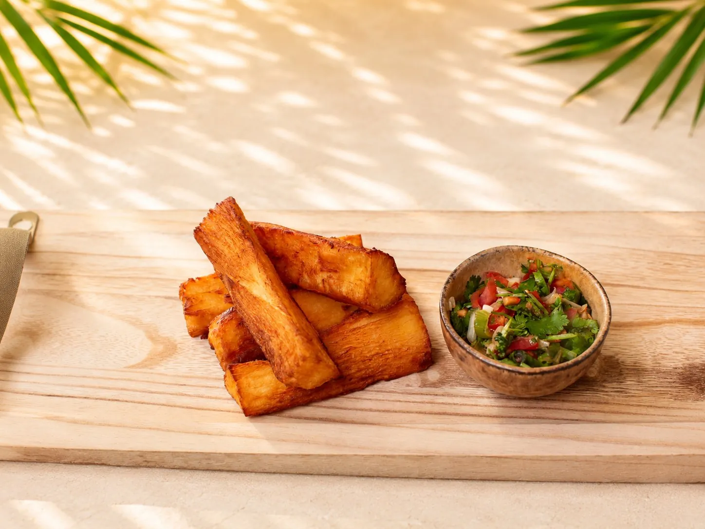 Frittierte Yuca-Stücke (Maniok), goldbraun und knusprig, serviert mit einer Schale Pico de Gallo.